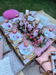 the table is set with pink and gold plates, napkins, candles, and flowers