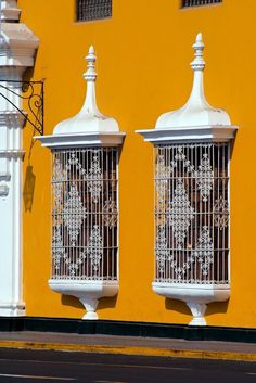 two white birdcages sitting on the side of a yellow building