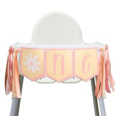 a white chair with pink and orange ribbons on it's legs, sitting in front of a white background