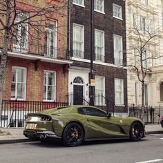 a green sports car parked in front of a tall brick building on a city street