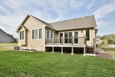 a large house sitting on top of a lush green field next to a fenced in yard