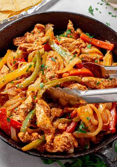 a skillet filled with chicken and peppers next to tortilla chips on a table