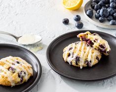 two black plates with blueberry scones on them and some lemons in the background