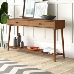 a wooden table with two drawers and a plant on it next to a white wall