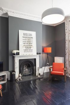 a living room with gray walls and orange chairs in front of the fire place is shown