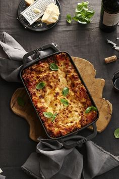 a casserole dish with cheese and spinach garnished with fresh basil