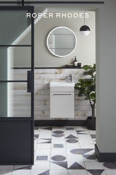 a bathroom with black and white tile flooring, a round mirror above the sink