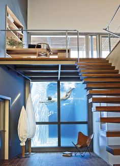 an indoor swimming pool with stairs leading up to the upper floor and above it is a wooden staircase