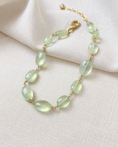 The color of these gorgeous prehnite gems reminds me of the sun shining through new spring leaves. They shimmer and glow with every movement, catching the light in the most enchanting way. I have wire-wrapped each faceted oval gem by hand in 14K gold fill, forming a simple, elegant chain. The extender allows for an adjustable fit for most wrists. Bracelet length: 7 inches plus 1-inch extender Materials: prehnite, gold fill Elegant Green Citrine Jewelry, Elegant Moonstone Gemstone Beads Jewelry, Oval Citrine Green Jewelry, Elegant Jewelry With Natural Stones And Chrysoprase, Oval Green Citrine Jewelry, Delicate Green Jewelry With Natural Stones, Elegant Chrysoprase Jewelry With Natural Stones, Elegant Peridot Jewelry With Natural Stones, Elegant Moonstone Healing Bracelet