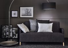 a living room filled with furniture and pictures on the wall next to a floor lamp