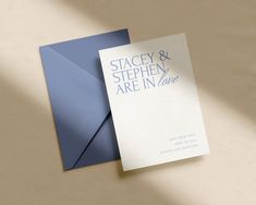 a blue and white wedding card on top of a brown envelope with the words, stagey & stephen are in love