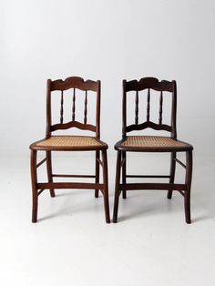 two wooden chairs sitting side by side on a white surface