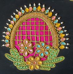 an intricately designed pink and green piece on a black surface with gold trimmings