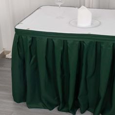 the table is covered with green cloths and has a wine glass on top of it