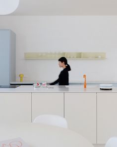 a man standing in front of a counter top next to a white table and chairs