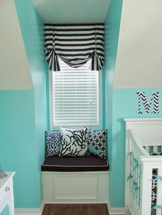 a baby's room with blue walls, black and white curtains and a window seat