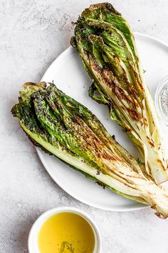 grilled artichokes on a white plate next to mustard and seasoning