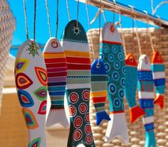 colorful fish ornaments hanging from a rope in front of a basket with blue sky behind them