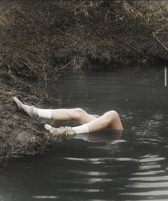 a man laying on his back in the middle of a body of water with mud around him