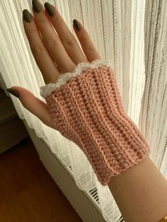 a woman's hand wearing a pink crochet wrist warmer