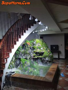 an indoor waterfall in the middle of a room with stairs leading up to another area