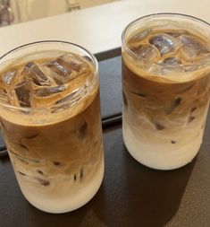 two iced coffees sitting on top of a table next to each other with ice