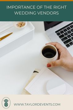 a person holding a cup of coffee in front of a laptop computer on a desk