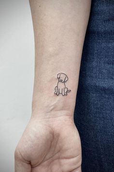 a small tattoo on the wrist of a person with a dog in it's hand