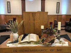 an open book sitting on top of a wooden table in front of a cross and candles