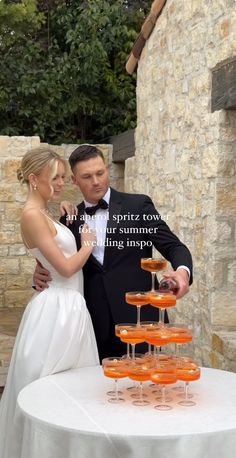 a man and woman standing next to each other in front of a table with glasses on it