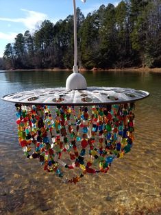 a chandelier hanging from the side of a body of water with trees in the background