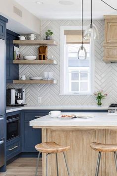 a kitchen with blue cabinets and wooden stools in front of an island countertop