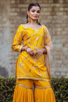 Mango yellow padded kurta with gota, thread, sequin embroidery in criss cross pattern. Paired with tiered gharara and dupatta.
Components: 3
Pattern: Embroidery
Type Of Work: Gota, thread, sequin
Neckline: Broad V neck
Sleeve Type: Long sleeves
Fabric: Dupion Silk, Viscose Georgette, Net
Color: Yellow
Other Details: 
Border embroidered sheer dupatta
Tiered pleated gharara
Embroidery on gharara hem
Back tassel tie-up
Attached lining
Approx. product weight: 2 kgs
Model height: 5ft 8inches, wearing Yellow Chinon Kurta With Mirror Work, Yellow Chinon Sets With Zari Work, Yellow Sets With Mirror Work In Traditional Drape, Yellow Traditional Drape Sets With Mirror Work, Yellow Traditional Drape Set With Mirror Work, Yellow Sets With Mirror Work For Eid, Festive Yellow Mirror Work Sets, Yellow Saree Set With Mirror Work, Festive Yellow Palazzo Set With Mirror Work