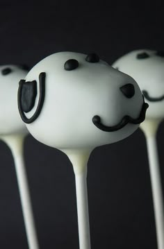 three cake pops with white frosting and black sprinkles decorated like smiley faces