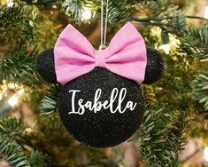 a minnie mouse ornament with a pink bow hanging on a christmas tree branch