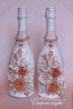 two white bottles decorated with flowers and pearls