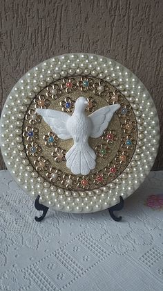 a decorative plate with a white bird on it's side and pearls around the edge