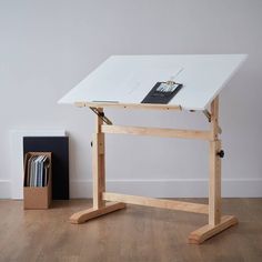 a desk with a white top and wooden legs in front of a book case on a hard wood floor