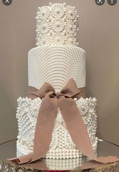 a three tiered wedding cake decorated with pearls and bows