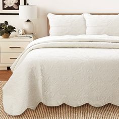 a bed with white bedspread and pillows in a bedroom