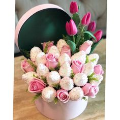 a bouquet of pink roses in a white vase on a table with a green hat