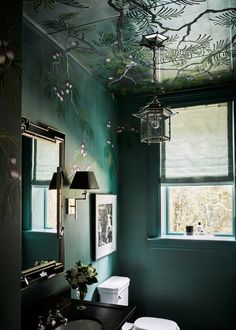 a bathroom with green walls and ceiling painted in the same color as the wallpaper