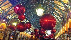 red christmas balls hanging from the ceiling in a shopping mall with lights on either side