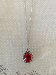 "This pretty oval shaped necklace in tibetan silver and red has an intricately designed edging with a red crystal center stone.   Pendant measures 1 1/8\" L X 3/4\" W and is on an 18\" chain.    ★ Want to see more?  Please visit my shop at: https://www.etsy.com/shop/DesignsByPeg" Cheap Red Spiritual Necklaces, Red Stone Pendant, Red Stone Jewelry, Red Stone Necklace, Red Crystal Necklace, Red Necklace, Red Gifts, Necklace Red, Cute Necklace