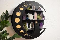 a black and gold clock mounted to the side of a wall next to a potted plant