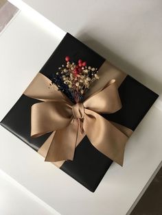 a gift wrapped in black and gold with a bow on it's side, sitting on top of a table