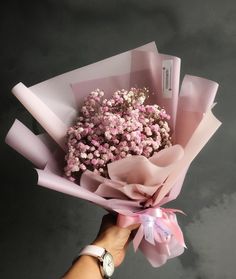 a hand holding a bouquet of pink and white flowers