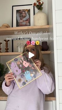 a woman holding up a piece of artwork in front of her face with the words mother's day gift idea pressed on it