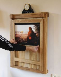 a person holding up a framed photograph on the wall