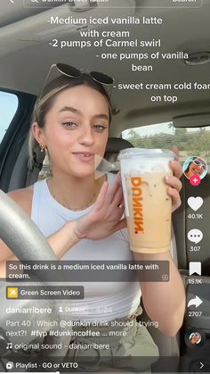 a woman is holding a drink in her car